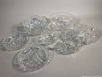 Full set of cut crystal items including 8” footed fruit bowl, honey jar with spoon, creamer, sugar bowl, and several bowls and dishes on a white background for condition review.