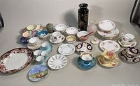 Full assortment of dishes, teacups, pottery, and vases displayed on table. Shows variety of designs and condition.
