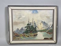 Framed oil painting showing mountain landscape with trees and river, minor frame damage visible
