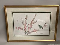 Framed watercolor painting showing a bird perched on flowering branches, overall view including gold-tone frame with minor wear.
