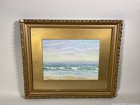 Overall framed view of the oil painting showing the gold ornate frame with the seascape painting center.