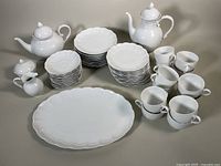 Full set overview showing all porcelain items including coffee pot, teapot, creamer, sugar bowl, platter, plates, cups and saucers.