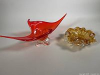 Both Murano art glass pieces: red freeform center bowl and smaller amber ashtray/bowl shown together.