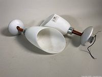 Pair of white conical wall sconces with wooden arms and round metal wall mounts, positioned horizontally.