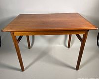 Front angle view showing rectangular teak coffee table with slightly tapered legs and wood grain surface.
