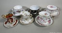 Six assorted teacup and saucer sets displayed together showing variety of floral and decorative designs.