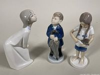 All three porcelain figurines together showing scale and comparative detail.