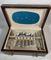 Wooden flatware chest open showing arrangement of flatware inside.
