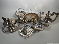 Photo showing all silver plated servingware items from above including teapot, coffee pot, sugar bowl, creamer, pedestal compote bowl, leaf-shaped dish, and trays.