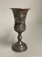 Front view of the vintage sterling silver Kiddush cup showing etched Judaica motifs and tarnishing.