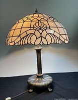 Front view of the lamp showing dome shade and brass-tone footed base