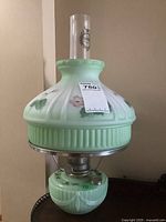 Full view of mint green glass Aladdin reproduction oil lamp showing base, font, floral pattern and clear glass chimney with Aladdin logo.