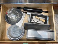 Top view showing multiple baking pans, tins, two rolling pins, and cooking items in drawer.