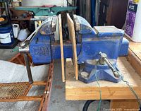 Photo of BM4 blue metal bench vise mounted on wooden workbench showing side with handle and wooden jaw covers.