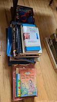 Stack of assorted hardcover and softcover books including children's storybooks and books about knots and fishing.