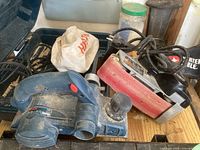 Bosch corded hand planer and Porter-Cable 3x21 corded belt sander shown on table with dust and cords.