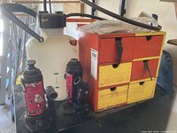 Overview of two bottle jacks, sprayer, small organizer, dowels and sanding paper