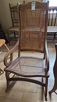 Straight-on photo showing the full wood rocking chair with caned seat and backrest.