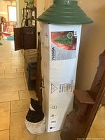 Photo of the NOMA 7 ft pre-lit spruce Christmas tree box with the green plastic tree stand on top and snowman door stop at base.
