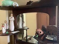 Photo of three Willow Tree figures and wooden puzzle elephant and frog on wooden shelf with mirror reflection.