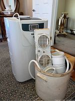 Photo showing white Danby floor air conditioner unit and stoneware crock with accessories inside.
