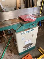 Side view of jointer showing cast iron infeed/outfeed tables, fence and model label