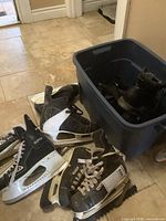 Photo of assorted hockey skates, boots, and walking spikes in and around a blue bin.