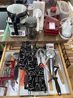 Full lot overview showing waffle maker, coffee grinder, mixer, slicer, oven mitts, and kitchen utensils.