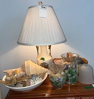 Full lot including lamp on wooden table, bowls and vases filled with sea glass and seashells.