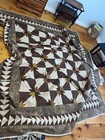 Quilt spread out on wooden floor showing full geometric pattern and border.