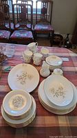 Photo of several pieces of Royal Doulton Yorkshire Rose china including plates, cups, saucers, small pitchers, arranged on a table with a plaid tablecloth