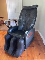 Angled view of black massage lounger showing overall condition, footrest and upholstery