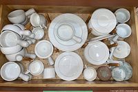 Top view showing the soup dishes with handles, plates stacked underneath, and six Oneida cups mixed among items.