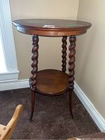 Side view of round top wooden table showing barley twist legs and lower shelf