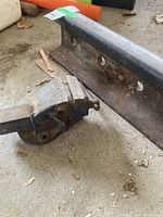 3-inch bench vice and 19-inch railway rail on concrete floor with wood debris