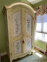 Full front view of a cream hand-painted armoire in place