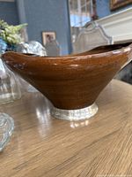 Wooden bowl with silver-colored metal base, curved design, smooth finish.
