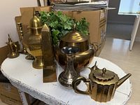 Group of assorted brass items on round white table