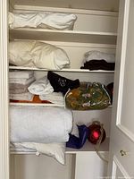 Overview of closets with folded linens, towels, blankets, and holiday decorations on shelves