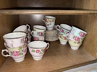 Shelf with 4 demitasse cups and 8 saucers with pink rose floral design and gold trim