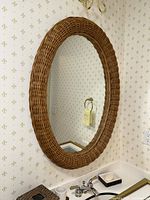 Large oval rattan framed mirror above bathroom sink with soap dish and cup holder visible