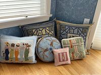 Group shot of all 6 custom embroidered pillows arranged on floor near wall