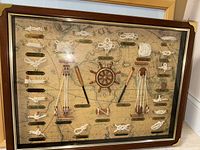 Wide view of shadow box showing multiple sailor knots with plaques and wooden nautical details on map background.