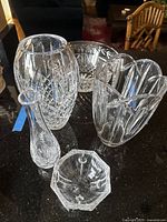 Seven heavy crystal pieces displayed on dark countertop showing intricate cut patterns and polished surfaces.