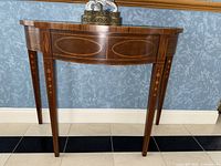 Front view of demi-lune table showing oval inlay on apron