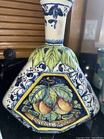 Large Italian pottery decanter with fruit motif and label showing handmade and decorative only marking.