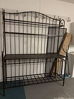 Front view of the large metal baker's rack with three shelves against a wall.