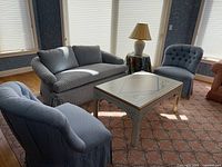 Wide view showing blue and white love seat, two blue side chairs, a painted coffee table, rug, and a lamp on a small table (not included).