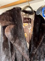 Dark brown full-length mink coat hanging on rod