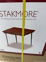 Top front view of box showing brand Stakmore and picture of folding table inside.